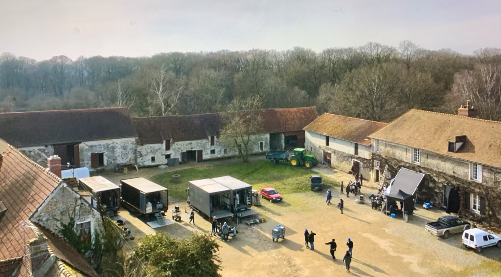 Plateau de tournage extérieur en Ile-de-France avec camions régie et logistique dans une cour de ferme authentique.