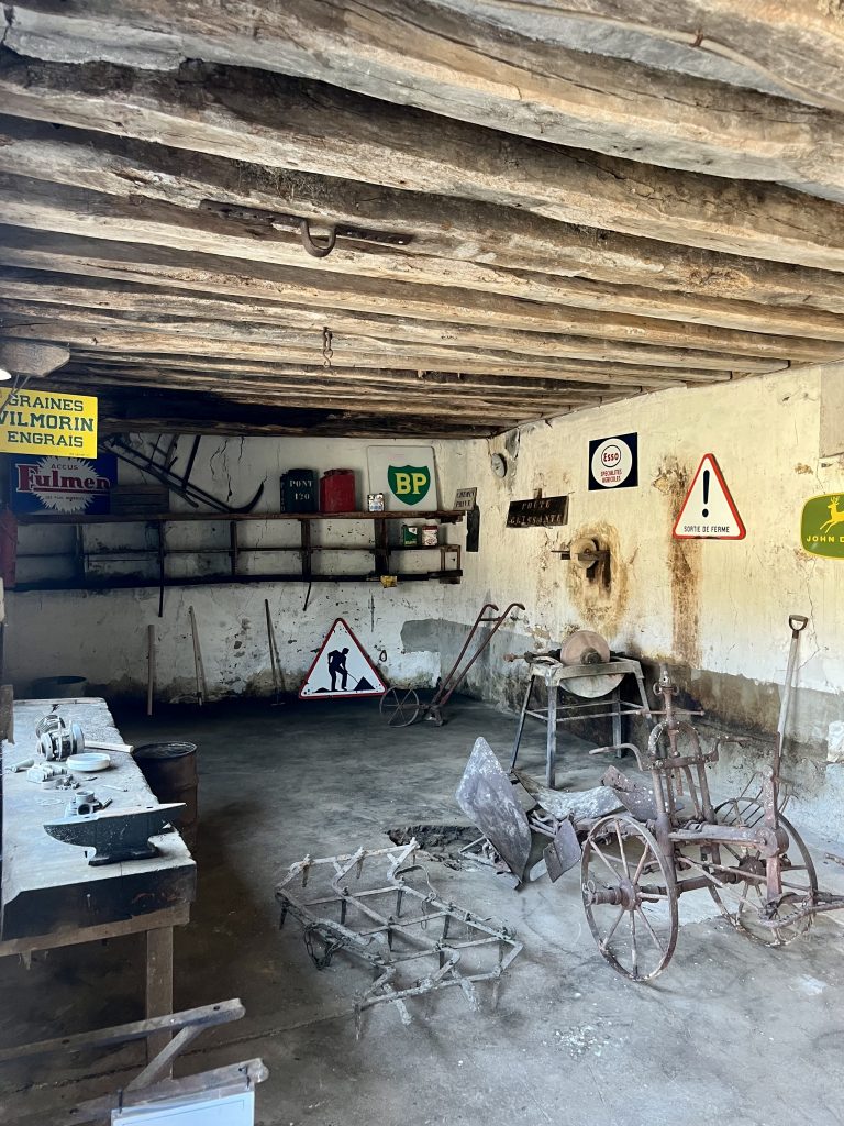 Atelier vintage avec plaques émaillées et outils agricoles anciens, décor tournage Essonne Île-de-France